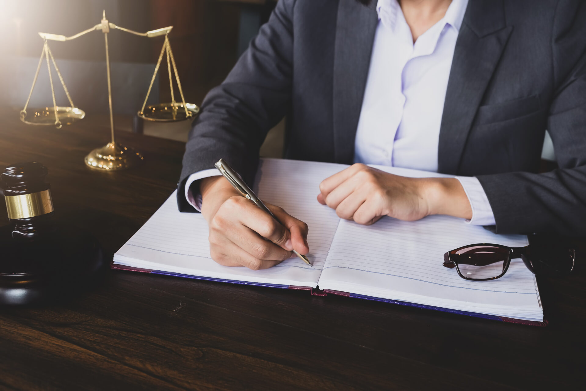 advice and justice concept. Justice scales and justice hammer and female lawyer use pen, working legal law at lawyer office. ACP Wind down
